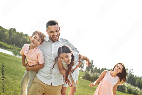Happy moments Positive and young father carrying his kids and smiling while spending time together outdoors