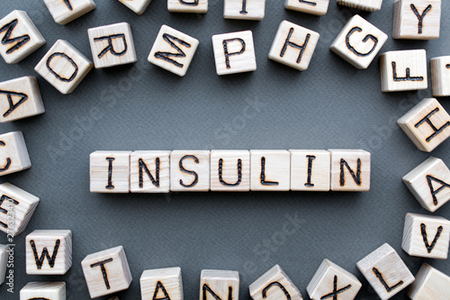 the word insulin wooden cubes with burnt letters, hormone insulin, diabetes treatment gray background top view, scattered cubes around random letters