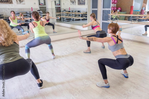 Young fit Women on a Yoga Pilates group class in gym. They stretch, stay in asana poses in sport outfit. Daylight. Indoors