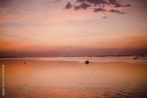 Evening sea, golden yellow light, small boat entering the shore