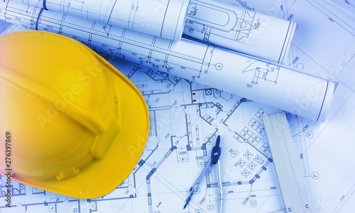 Blueprints construction and a yellow hardhat with a compass