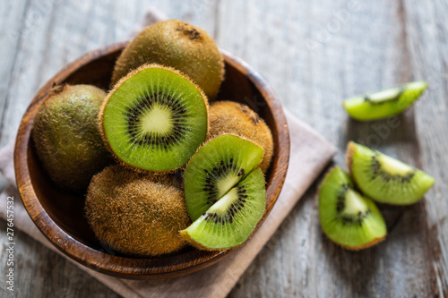 Fresh kiwi fruit in the bowl on wooden background