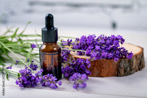 lavender herbal oil and flowers on wooden background