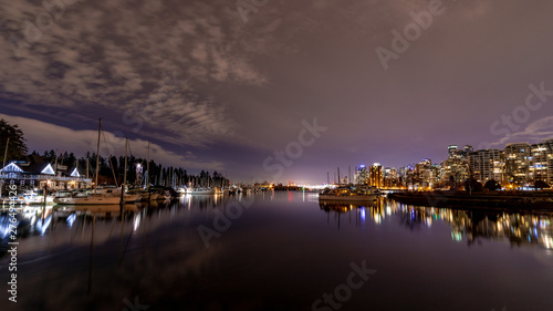 Vancouver, BC \ Canada - 13 March 2019: A night long exposure photo of yachts and boats in marina of Burrard Inlet of Vancouver Harbor. City skyline and Canada place lights are in the background