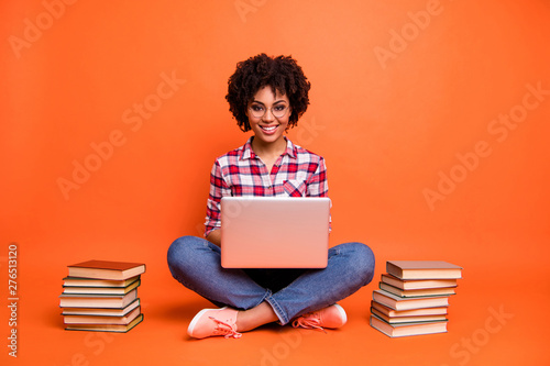 Full length photo curly beautiful lady sit floor hold hands notebook online courses wear specs casual checkered plaid shirt isolated orange background