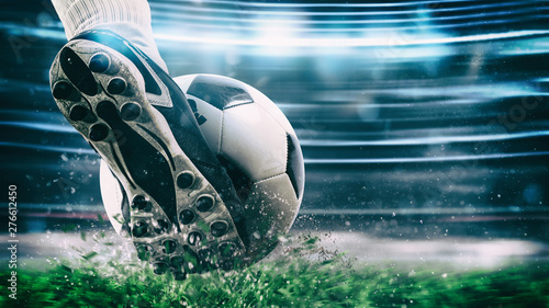 Football scene at night match with close up of a soccer shoe hitting the ball with power