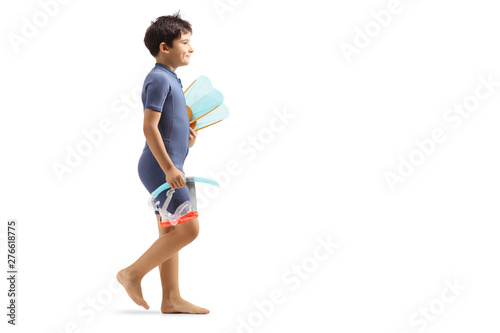 Boy in a wetsuit walking and holding a diving mask and flippers