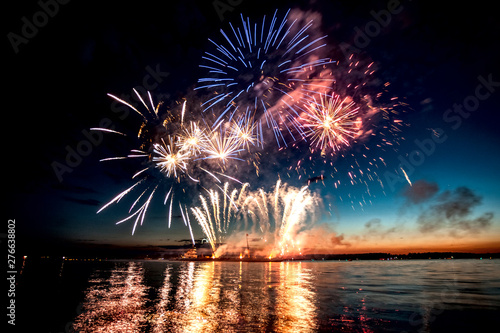 Holiday fireworks above water with reflection on the black sky background