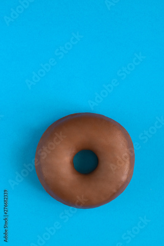 Close up of classic chocolate donut on blue modern background. Copy space