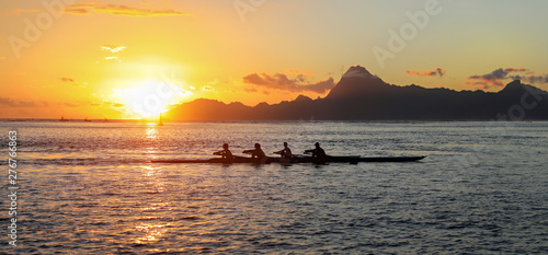 Silhouette view of 4 long boat crew rowers in the pacific ocean at sunset. 