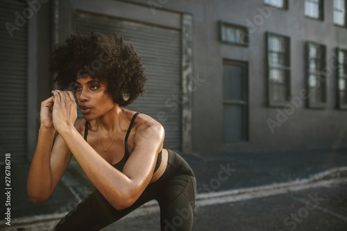 Young woman exercising squats in city