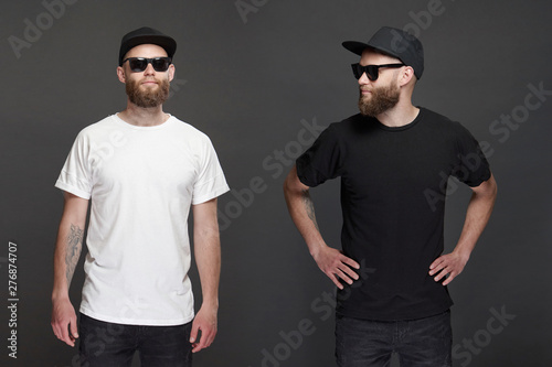 Hipster handsome male model with beard wearing white blank t-shirt and a baseball cap with space for your logo or design in casual urban style.