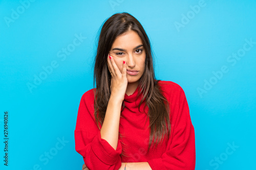 Young woman with red sweater over isolated blue background unhappy and frustrated