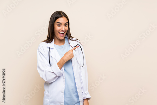 Young doctor woman over isolated background pointing finger to the side