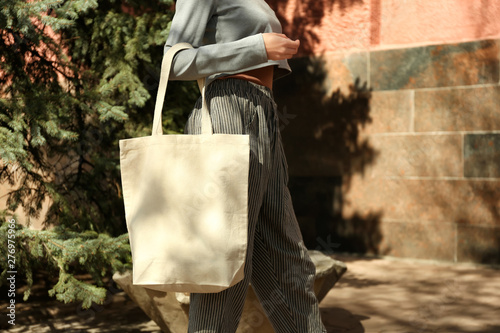 Young woman with cotton bag on city street, closeup. Mockup for design