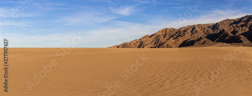 Sand dunes in a desert landscape in Death Valley California. The vast barren land is dry and arid due to droughts result of global warming and climate change.