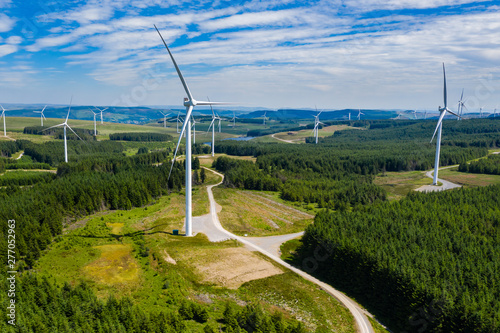 Aerial drone view of turbines at a large onshore windfarm on a green hillside (Pen y Cymoedd, Wales)