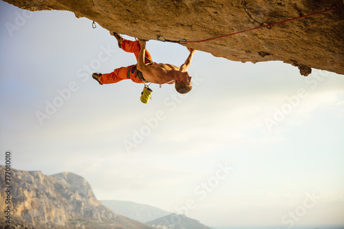 Young man climbing on ledge in cave before sunset