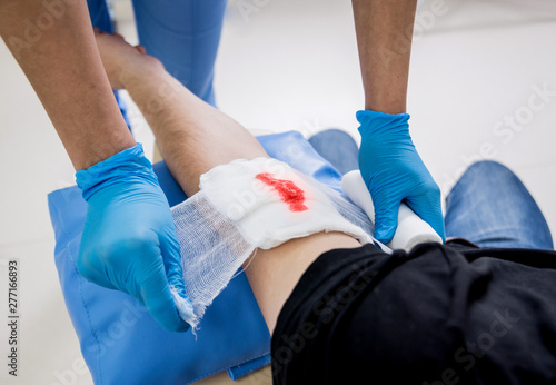 Nurse dressing wound for patient's hand with deep skin cutting.