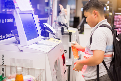 The boy is scanning the product at the automatic payment machine. self service machine in modern supermarket, self-service pay point tills, self-checkout machine in hypermarket, Bangkok Thailand.