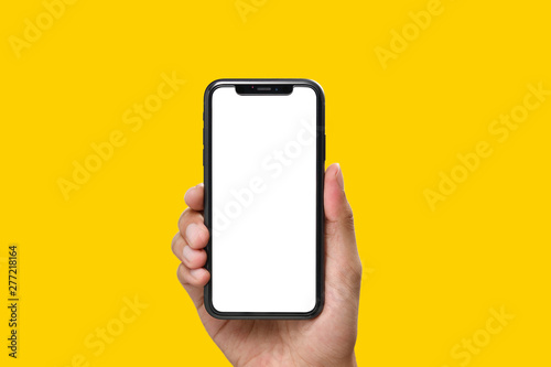 Hand holding the black smartphone with blank screen and modern frame less design on yellow colour background