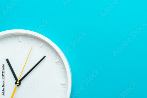 Part of white wall clock with yellow second hand hanging on wall. Close up image of plastic wall clock over turquiose blue background with copy space. Photo of time management or time is going concept