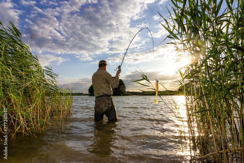 angler catching the fish in the lake during summer day