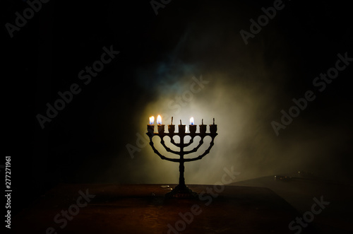 Low key image of jewish holiday Hanukkah background with menorah on dark toned foggy background