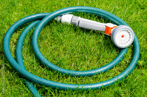 Green hose for watering lies on grass, lawn