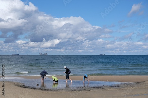 Poland, Gdansk, Baltic Sea - young people collecting shells and amber on Jelitkowo beach