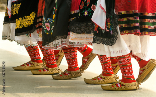 Girls dancing folk dance. People in traditional costumes dance Bulgarian folk dances. Close-up of female legs with traditional shoes, socks and costumes for folk dances.