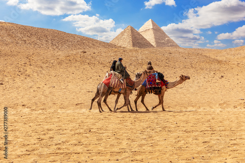 Egyptian men on camels in the sands of Giza near the Pyramids