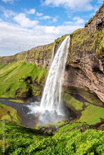 Charming beautiful waterfall Seljalandsfoss in Iceland with rainbow. Exotic countries. Amazing places. Popular tourist atraction.