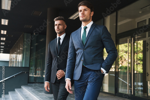 Portrait closeup of two concentrated businessmen partners walking together outside job center during working meeting