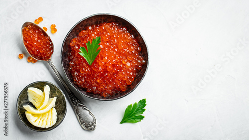 Delicious red caviar in black bowl on a light concrete background. Top view with copy space. Flat lay