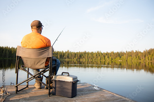 A man fishing on a lake on a wooden dock in Ontario Canada