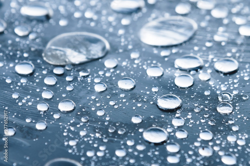 Close-up of raindrops of different sizes on the surface covered with cling film. Moisture weather and humidity concept
