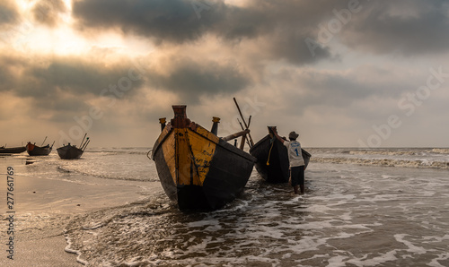 Digha, West Bengal, India. May 30,2019. Fishermen struggling to towing their fishing boat into the ocean before going for Fishing.