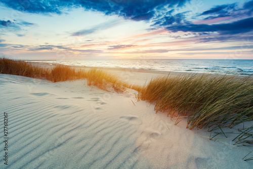 Trawiaste wydmy i Morze Bałtyckie o zachodzie słońca