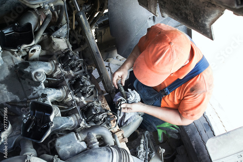 Mechanic repairs a truck. adjustment of valves of the diesel motor. Replacement nozzles.