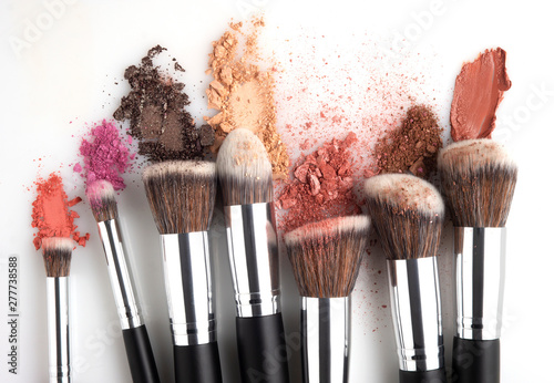 Creative concept beauty fashion photo of cosmetic product make up brushes kit with smashed lipstick eyeshadow on white background.