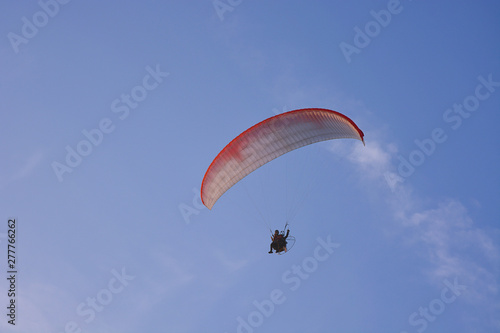 Paramotor (Powered Paraglider) With Red-White Parachute Flying In Sky, Extreme Sport.