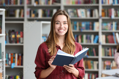 Young pretty woman with book in library