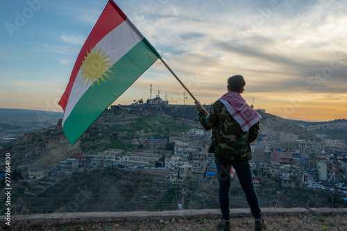 Teenager holding the Kurdistan flag in northern Iraq at sunset time on Nowruz 2019