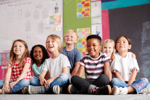 Group Of Elementary School Pupils Sitting On Floor In Classroom