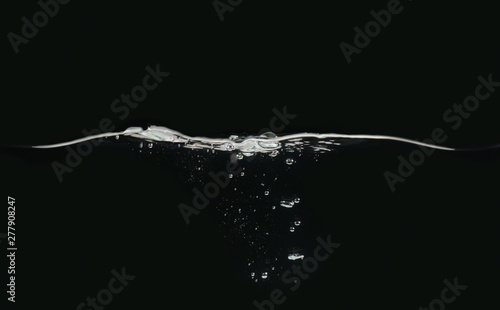 Waving water surface and small bubbles underwater isolated on black background, close up view. Perfect for compositing into your shots. Ready to use blending mode to screen or add