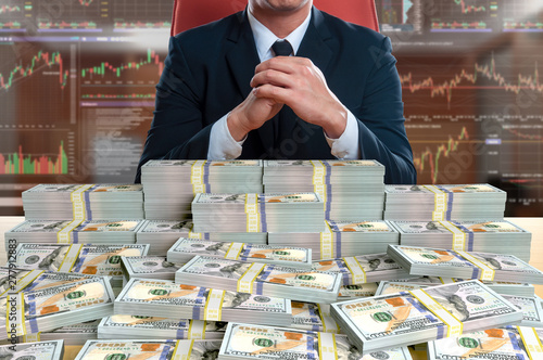 businessman sitting with pile of 100 dollar banknote