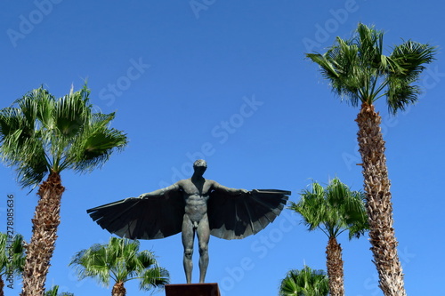 Statue d'Icare. Ailes déployées. Ciel bleu.