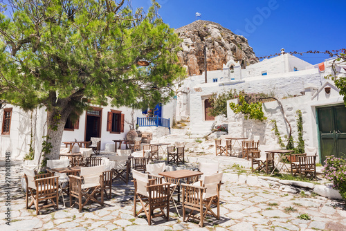 Traditional greek street with flowers and cafe tables in Amorgos island, Cyclades, Greece