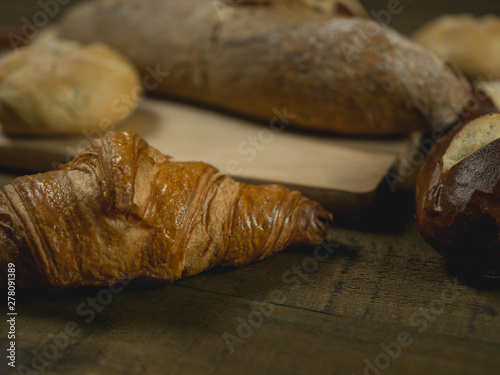 Rogalik croissant w zbliżeniu leżący na drewnianym stole